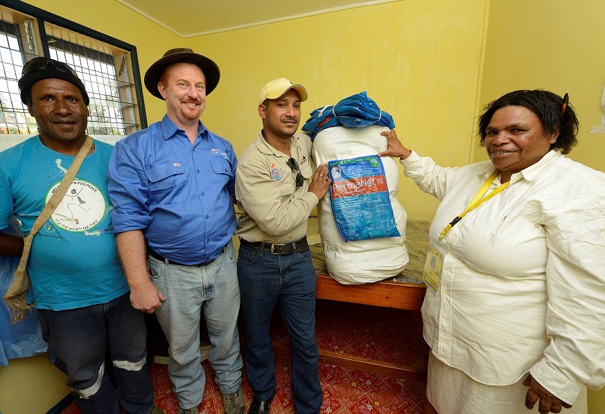 Development Manager in blue shirt with partners receive bed nets for distribution in the province