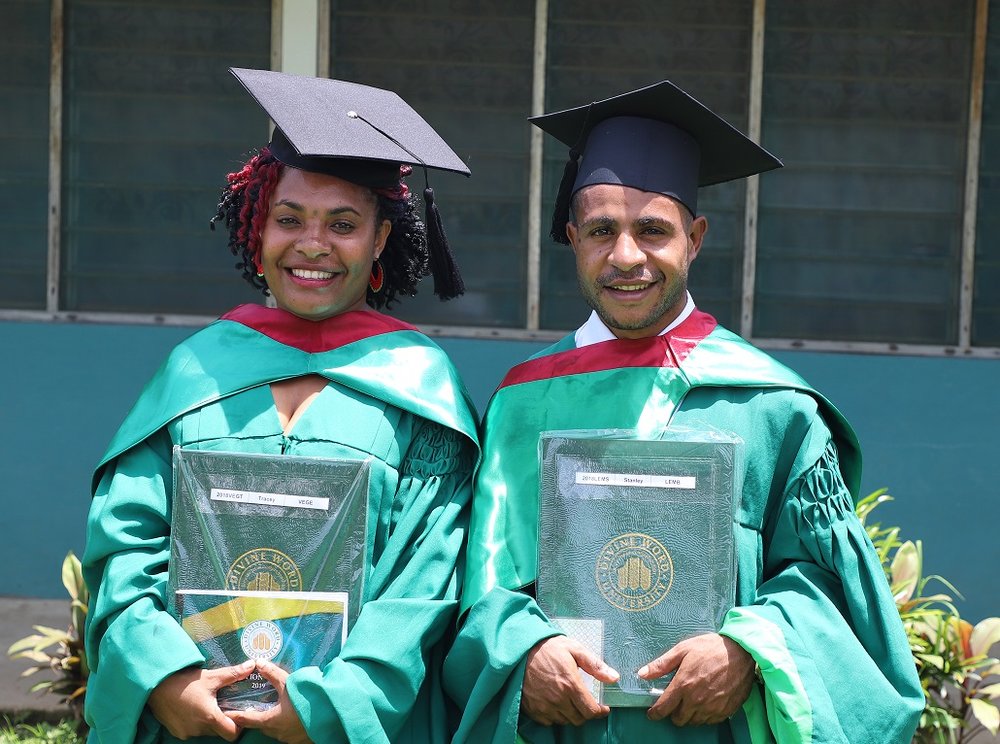 two scholarship recipients holding their awards in graduation garments