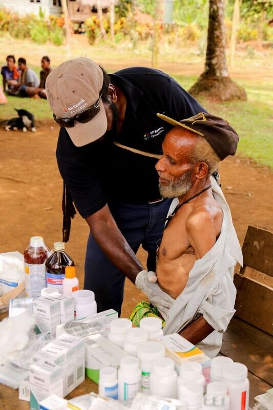 A health services member wearing gloves carries out health checks on a local patient 